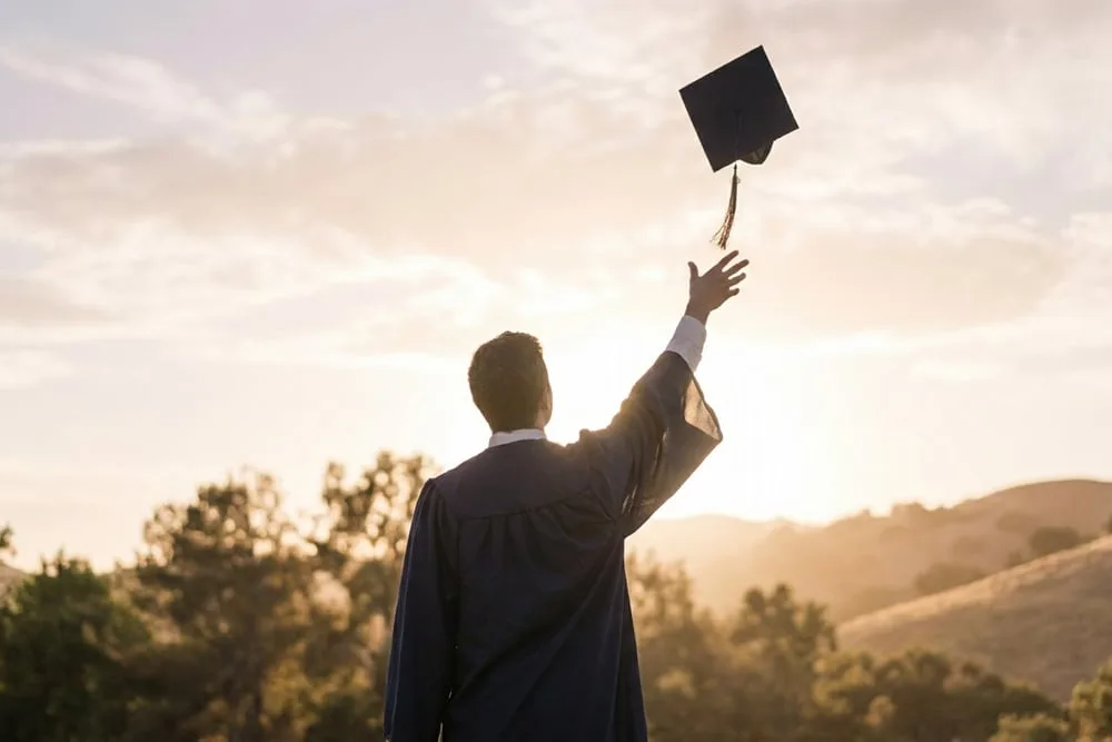 A graduation cap and rolled diploma